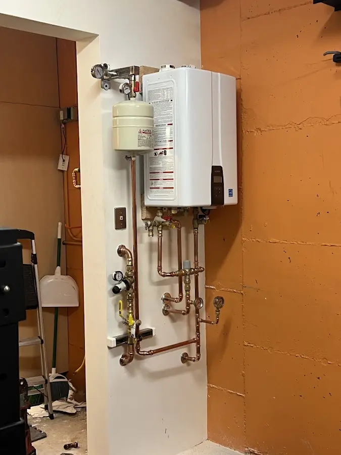 Plumbing technician inspecting water heater connections in Mascot